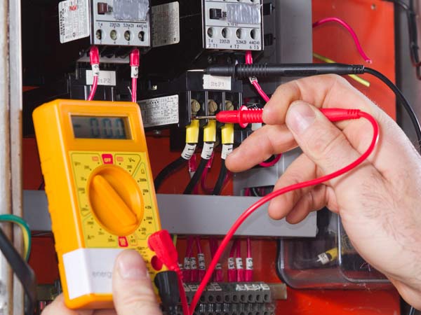 electrician testing electrical panel with voltmeter